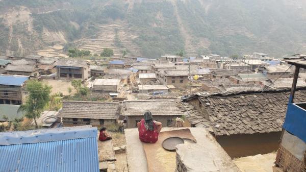 A woman sits on a platform overlooking rolling hills.