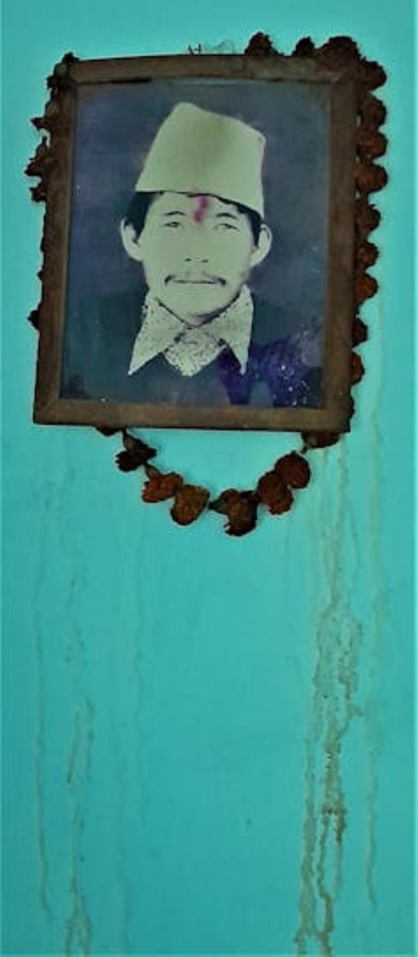 A picture of a man in a f<em></em>rame hangs on a green wall.