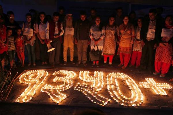 People stand in front of a candle memorial.